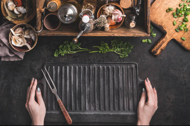 istock Woman hold empty cast iron grill griddle and meat fork on roast rustic kitchen table. 1388911206