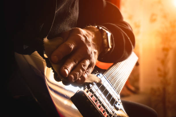 istock A young man wipes dust off an electric guitar. close-up. Sun rays. 1388911662