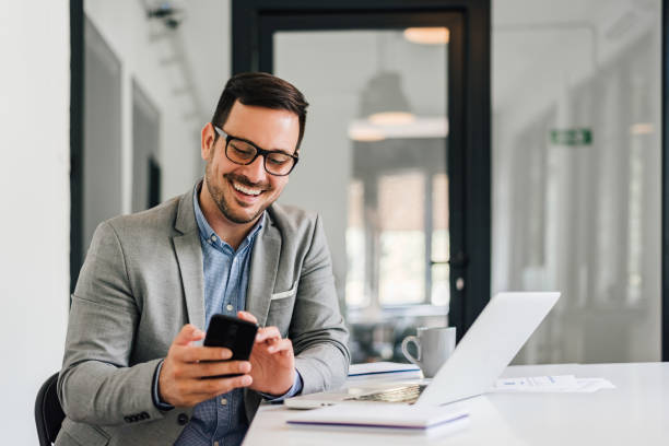 istock Joyful businessman, using his phone, in the office. 1388911806