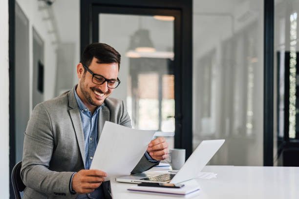 istock Smiling, caucasian businessman, reading a document. 1388911835