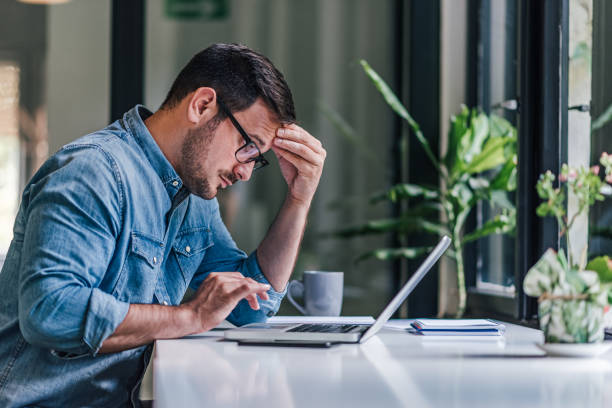 konzentrierter erwachsener mitarbeiter, der bei der arbeit an einem problem feststeckt. - frustration computer confusion businessman stock-fotos und bilder