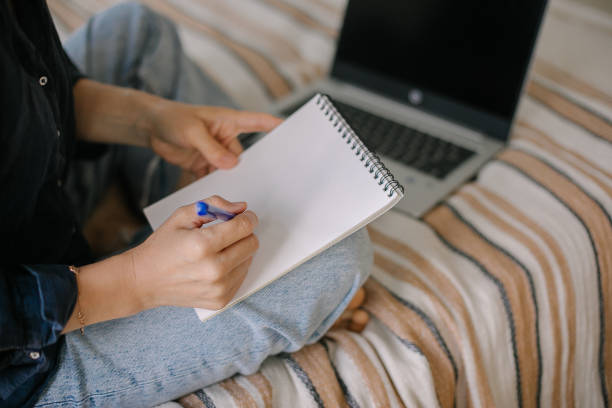 istock Female freelance writing down thoughts and ideas while working online on laptop from home 1388915918