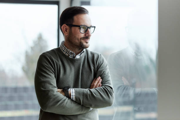 istock Young smiling man with crossed arms by the window. 1388916690