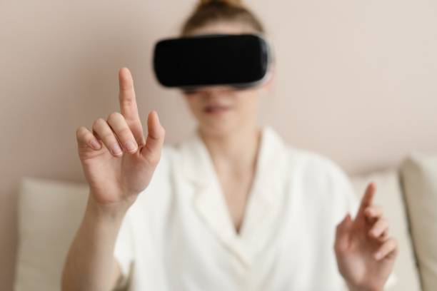 istock Enjoying new reality. Attractive young woman in VR headset gesturing and smiling while sitting at home. 1388918122