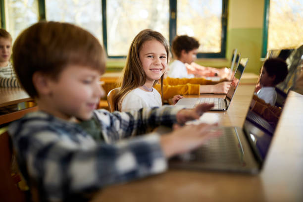istock Happy schoolgirl using laptop on a class at elementary school. 1388919306