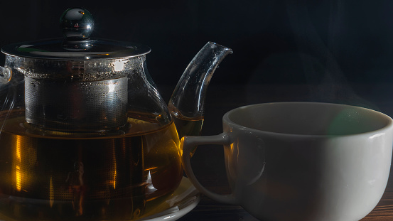 Tea cups and tea pot against black background with copy space, full frame horizontal composition