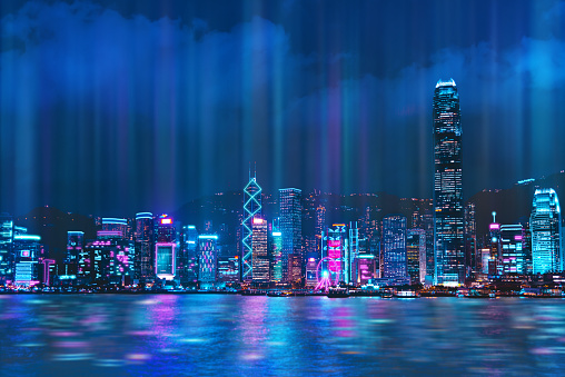Paisaje urbano del horizonte de la ciudad de Hong Kong por la noche sobre el puerto de Victoria con reflejo en el puerto, estilo de color Cyberpunk. photo