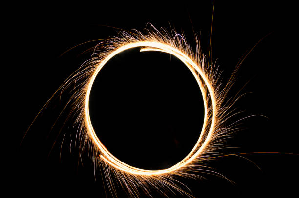 Stock photo showing close-up, elevated view of lit ground Catherine wheel showering out sparks as it spins on the ground as part of Diwali, the Indian traditional festival of lights.