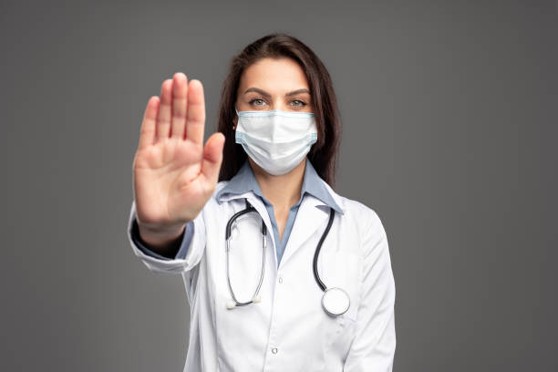 Nurse in mask gesturing stop stock photo