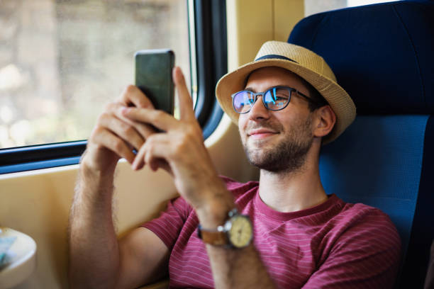 istock Caucasian male tourist, using mobile phone while travel in the train 1388924513