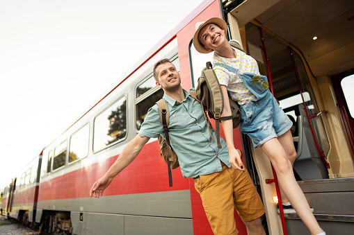 Urban young Caucasian couple holding hands, ready to travel together with train