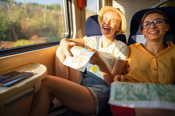 Cheerful female friend stravel together with train At the train, carefree Caucasian female tourist looking at the city map exchange student stock pictures, royalty-free photos & images