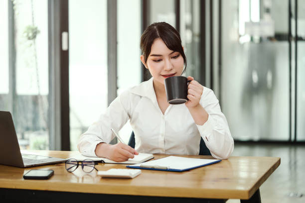 istock Asian businesswoman drinking coffee while working in the office. 1388925470