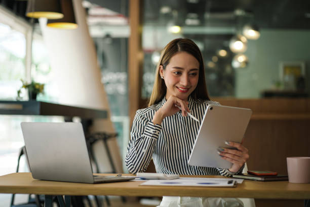 istock Young Asian business woman using tablet, looking at tablet screen, feeling happy and smiley. 1388925487