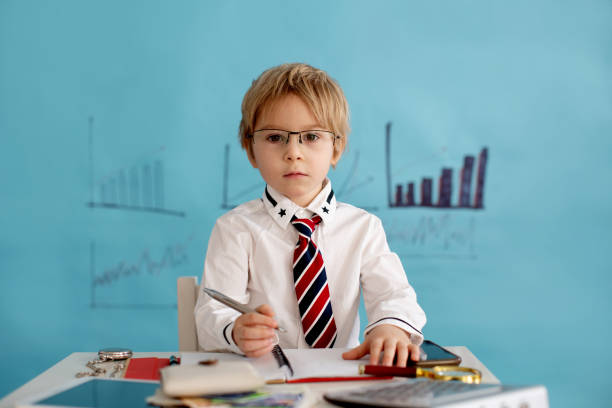 istock Good looking, smart casual dressed child, blond boy with tie, working on tablet, taking notes and talking on the phone, business concept 1388926283