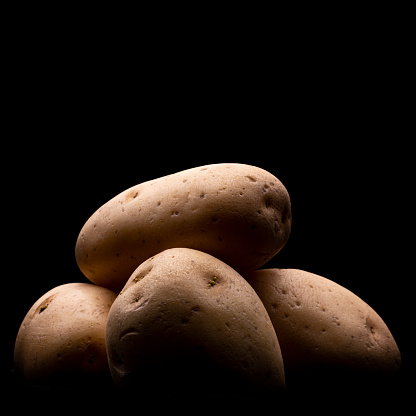 Low light macro photo of potatoes on a black background. Image with copy space