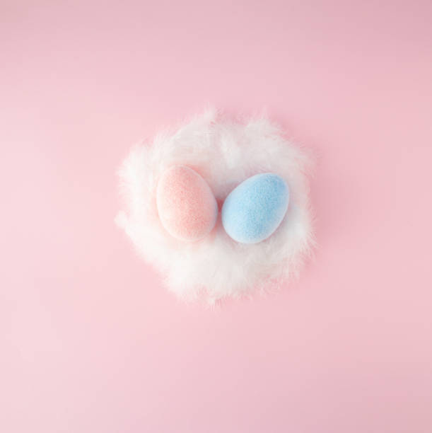 istock Easter scene with pink and blue egss in white feathered nest on pink background. 1388926815