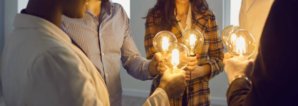 istock Business people join light bulbs as metaphor for sharing ideas in creative community 1388927124