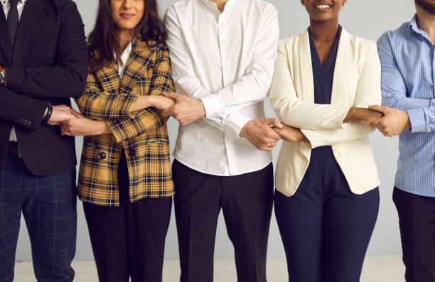 istock Business team standing in line holding hands together midsection studio shot 1388927140