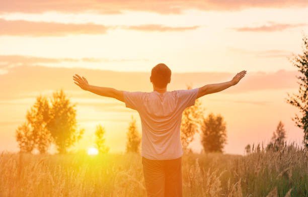 istock Freedom. A man looks at the setting sun with his arms outstretched 1388927420