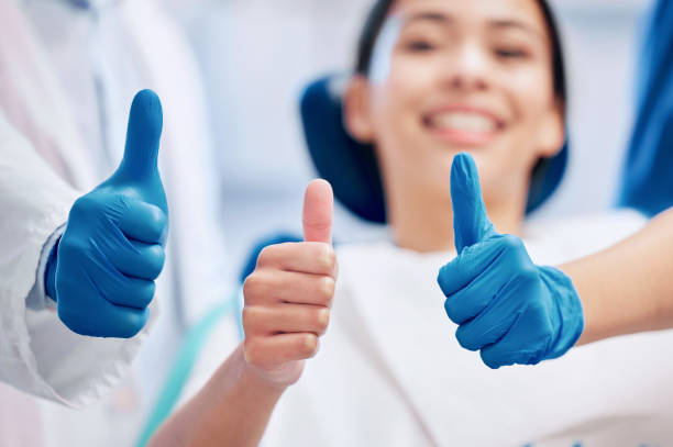 Shot of a young woman giving the thumbs up with her dentist Happy to have a great dentist dental health stock pictures, royalty-free photos & images