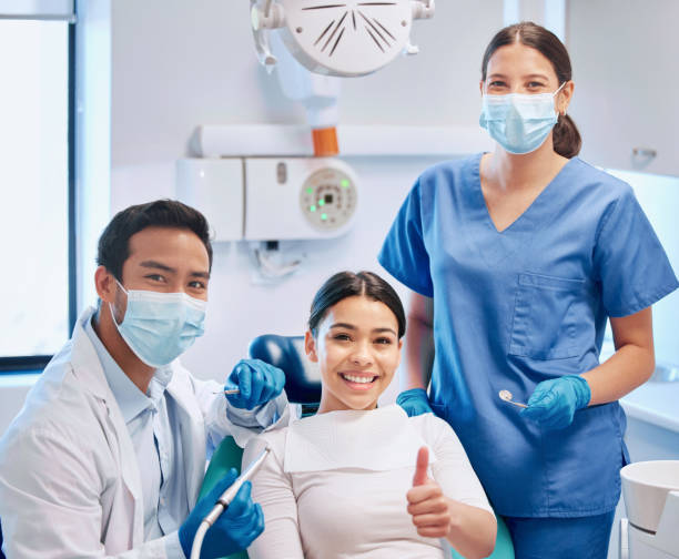 scatto di un giovane dentista maschio che dà il pollice in su con il suo paziente e assistente - dentist dental hygiene smiling patient foto e immagini stock