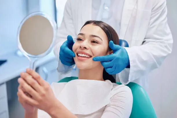 Photo of Shot of a young woman checking her results in the dentists office