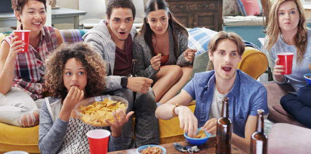 istock Shot of a group of friends enjoying snacks and drinks while watching something 1388931889