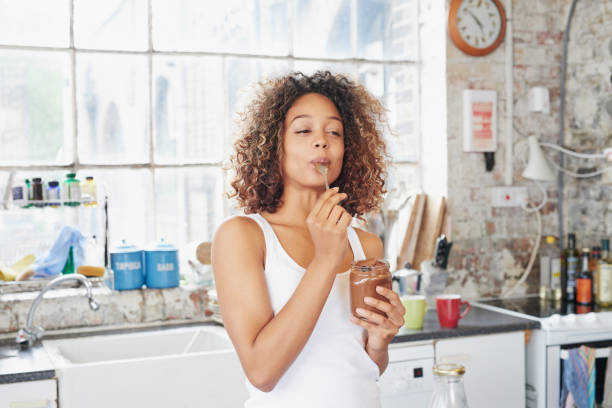 foto de una mujer joven comiendo una crema de chocolate del frasco - tasting women eating expressing positivity fotografías e imágenes de stock