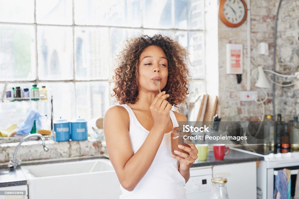 Shot of a young woman eating a chocolate spread from the jar This is so delicious Eating Stock Photo