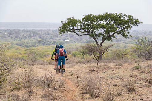 Two male mountainbiker are riding a narrow trail nearby Lake Chala in scenic savannah landscape of Tanzania.\nCanon EOS 760D, 1/250, f/8, 107 mm.