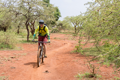 A male mountainbiker is riding through scenic savannah landscape nearby Lake Chala in Tanzania.\nCanon EOS 760D, 1/160, f/14, 35 mm.