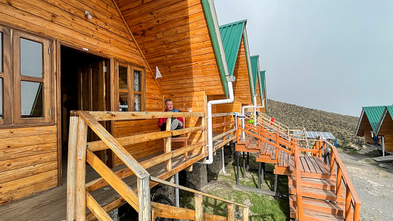 A male hiker is realxing on the gallery after hiking uphill at one of the new Horombo Huts (3.720 mt., 12.205 ft.) in the late afternoon. These huts are a very important base for support and acclimatization on the way up to the summit of Mount Kilimanjaro (5.895 mt., 19.341 ft.) on the Marangu route.