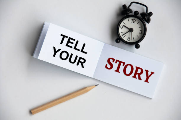 istock Tell your story text on notepad with alarm clock and pencil on white background. Conceptual 1388936204