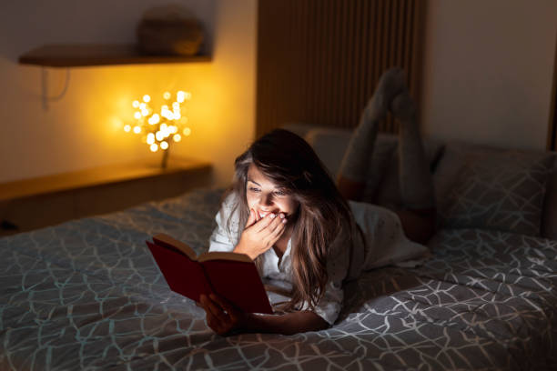 istock Woman lying in bed reading a book 1388937642