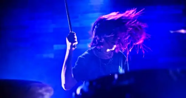 Photo of Close-up of girl emphatically playing the drums in twinkling strobe lights