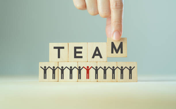 istock Teamwork and success concept. Work collaboration for achieving goal and successful business. Initiation for planning to reach target. Hand holds wooden cubes with TEAM text and teamwork icons. Banner. 1388939189