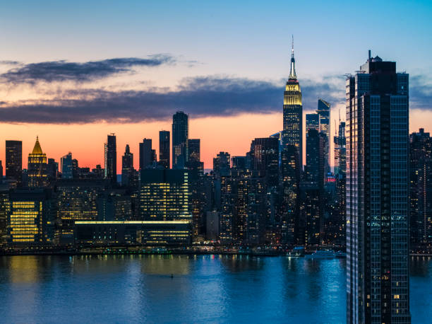 vista aerea a manhattan midtown dal queens, sugli edifici residenziali di lusso del lungomare di long island city, con il cielo drammatico illuminato al crepuscolo tardivo. - dramatic sky manhattan moody sky new york city foto e immagini stock