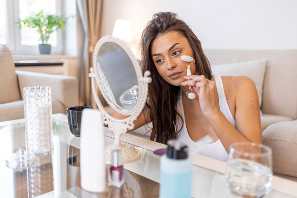 istock Beautiful young female massaging face by roller. 1388940399