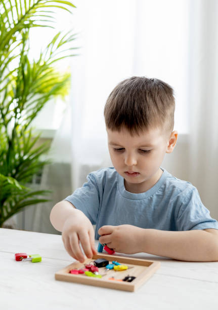 istock Montessori material. Boy are studying a puzzle with keys and locks. 1388942389