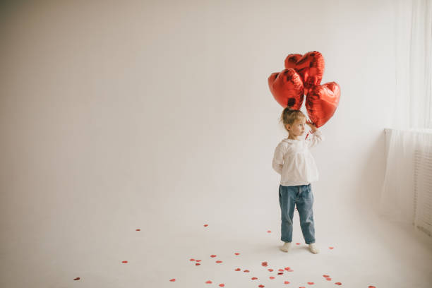 cute girl holding red heart shaped balloons on white background. saint valentine's day celebration. - heart shape confetti small red imagens e fotografias de stock