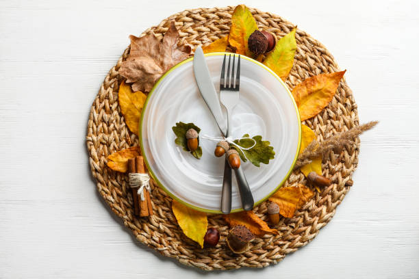 istock Autumn table setting with dry leaves on white wooden background, flat lay 1388947156