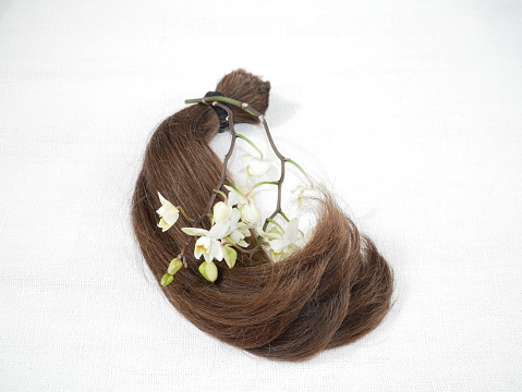 Cut human hair and orchid flowers. Concept of hair donations.