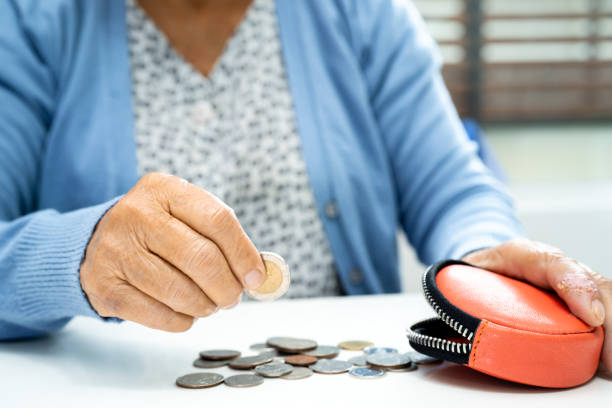 Asian senior or elderly old lady woman holding counting coin money in purse. Poverty, saving problem  in retirement. stock photo