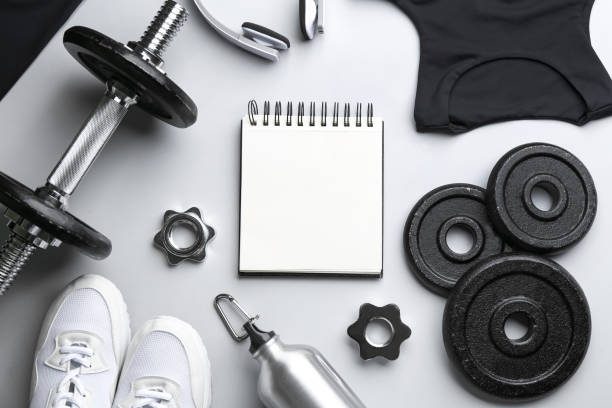 istock Flat lay composition with sportswear, notebook and equipment on light grey background. Gym workout plan 1388950032