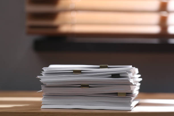 istock Stack of blank paper with binder clips on wooden table indoors. Space for text 1388950123