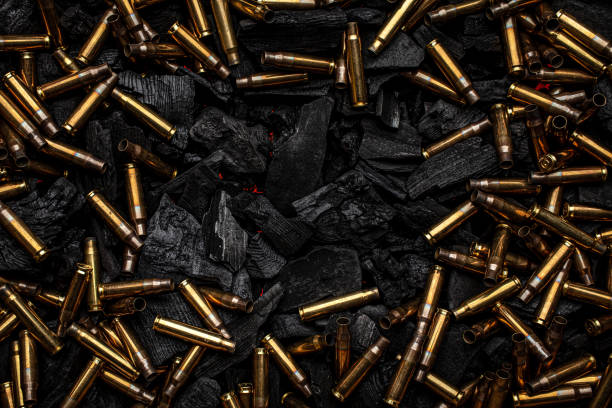 istock Empty shells from weapons on black smoldering coals. Consequences of the war. Dark background. 1388951292
