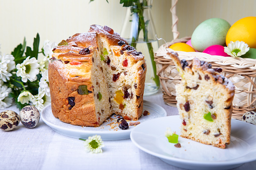 Cruffin with raisins and candied fruits. Easter cake, painted eggs and chrysanthemums. Easter holiday. Close-up, selective focus.
