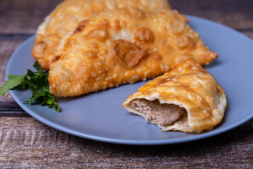 Chebureks with meat. Deep-fried flat cake. A traditional dish. Close-up, selective focus.