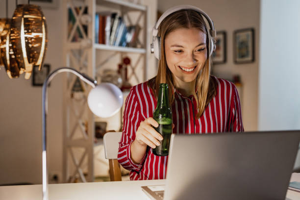 istock Young woman drinking beer while using laptop late at night 1388953591